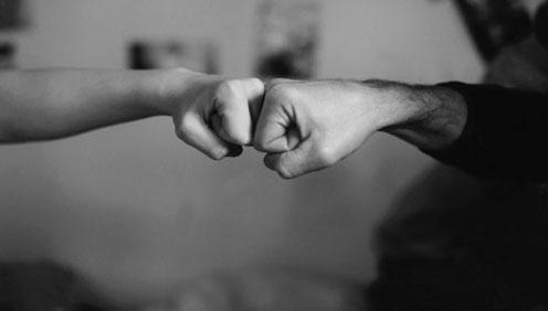 A black and white photograph of two fists bumping together