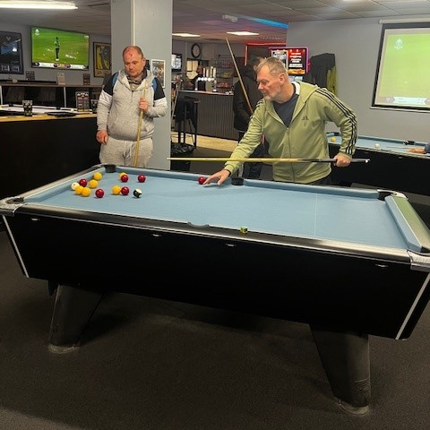 A photograph of 2 people playing pool