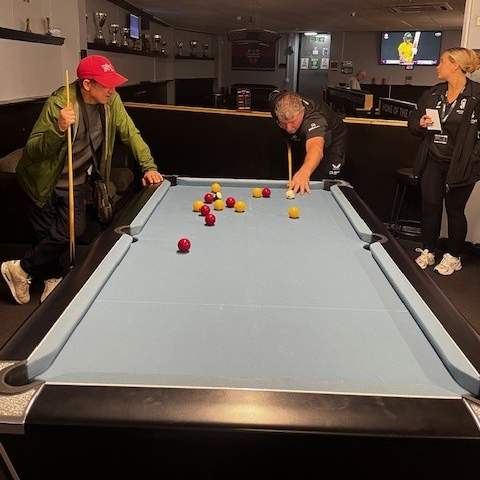 A photograph of people taking part in the pool tournament