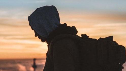 A photograph of a silhouette figure against a sunset looking out over the sea